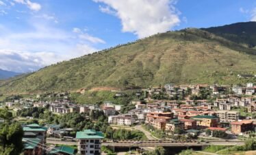 A picturesque view of a mountain town featuring a bridge and residential buildings.