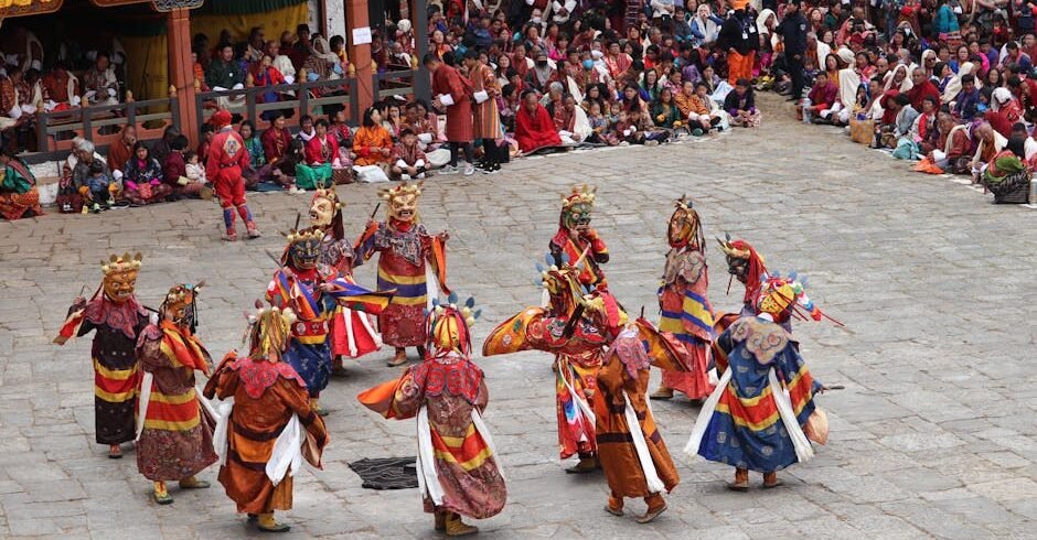 Colorful masked dancers performing at a traditional Bhutanese festival, surrounded by a large crowd.