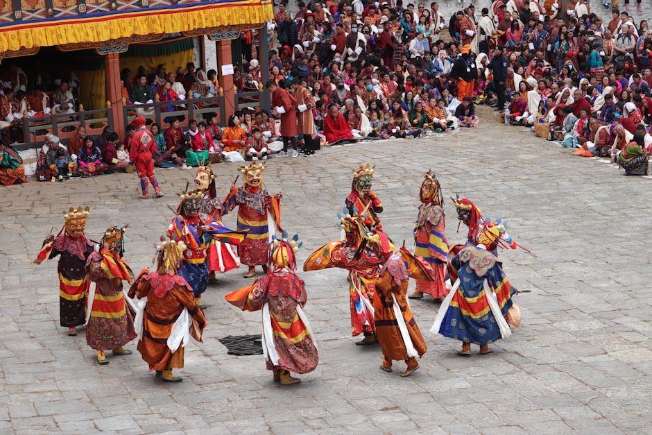 Colorful masked dancers performing at a traditional Bhutanese festival, surrounded by a large crowd.
