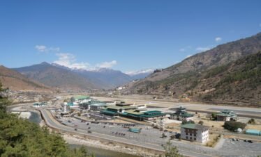 Aerial view of Paro Airport surrounded by mountains, showcasing Bhutan's stunning landscapes and unique architecture.